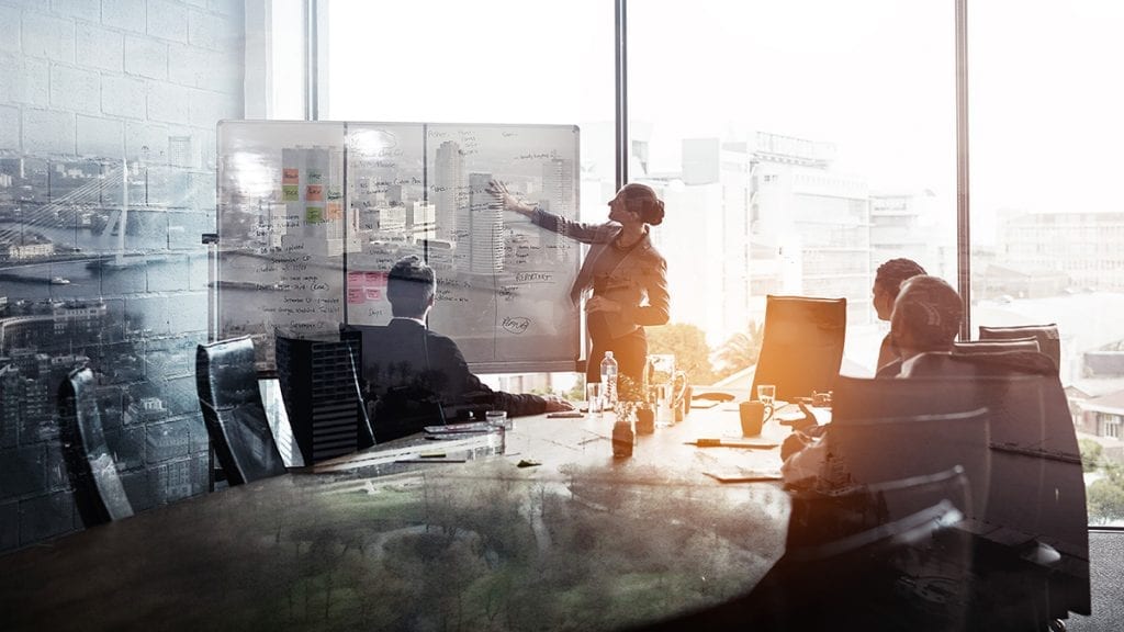 Woman pointing to a whiteboard during a meeting in a modern boardroom