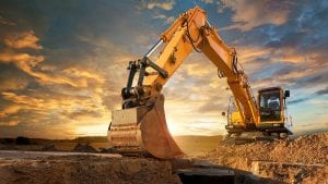 Excavator at a construction site against the setting sun.