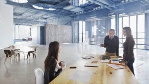 Colleagues meeting at table in large open lobby