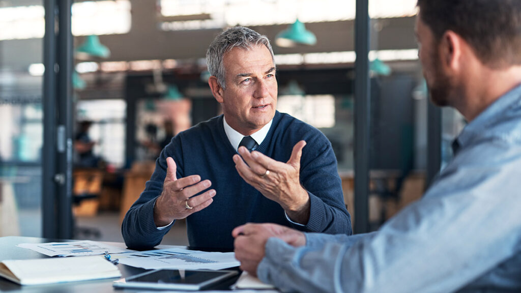 Two business men sitting at a conference table engaging in effective negotiating.