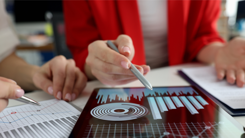 A person holding a pen over a graph on a touch screen.